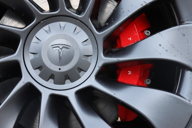 Close up view of the wheel on a Tesla where there is a brake caliper visible through the rim.
